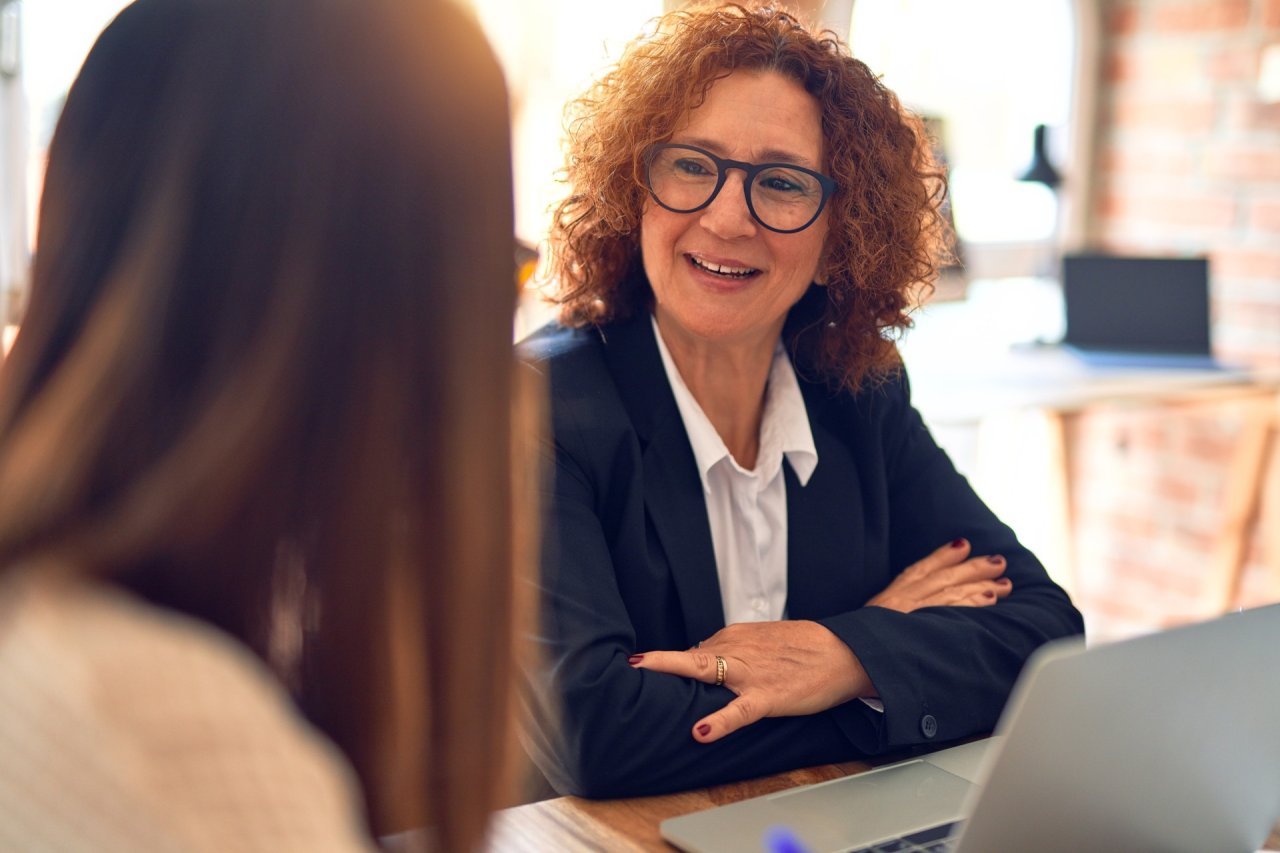 two businesswomen having a conversation, smiling.